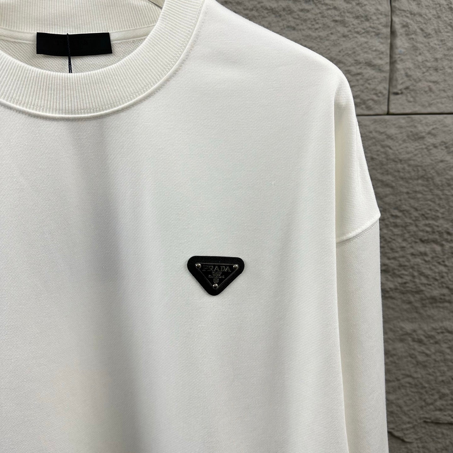 Off-white Prada crewneck sweatshirt with small black triangular logo patch.