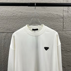 Off-white Prada crewneck sweatshirt with black triangular logo patch on chest.