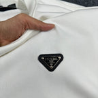 Off-white Prada sweatshirt fabric with black triangular logo patch, held by hand.