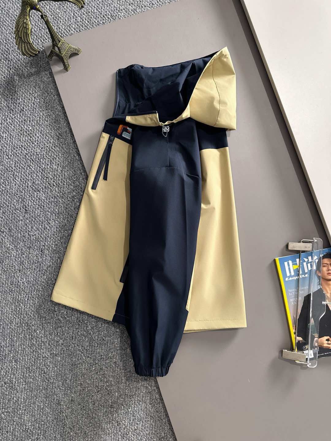 Hooded windbreaker jacket back view in navy with light yellow panels and long sleeves