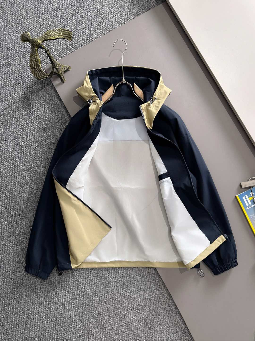 Hooded windbreaker jacket front view in navy with light yellow panels and zip closure