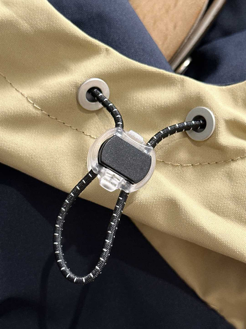 Adjustable drawstring cord lock on hood, on navy and light yellow windbreaker jacket