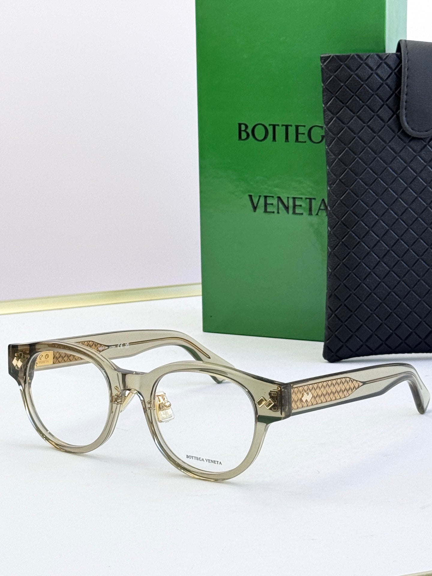 Bottega Veneta clear olive round eyeglasses with gold patterned temples and metal hinges