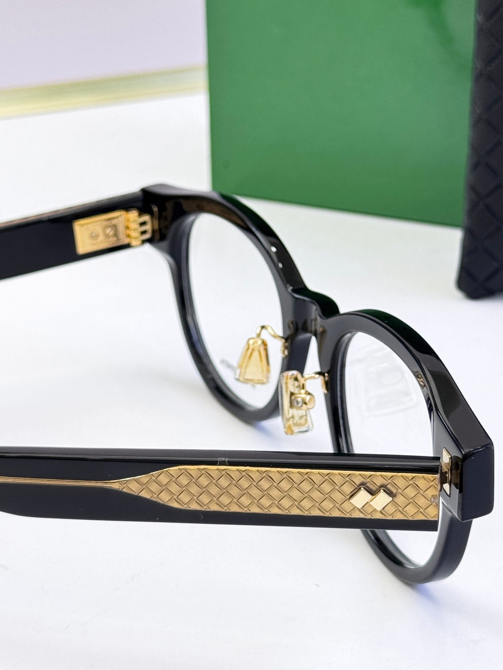 Bottega Veneta black round eyeglasses side view with gold patterned temple band