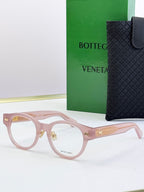 Bottega Veneta pink round eyeglasses with gold patterned temples and metal hinges