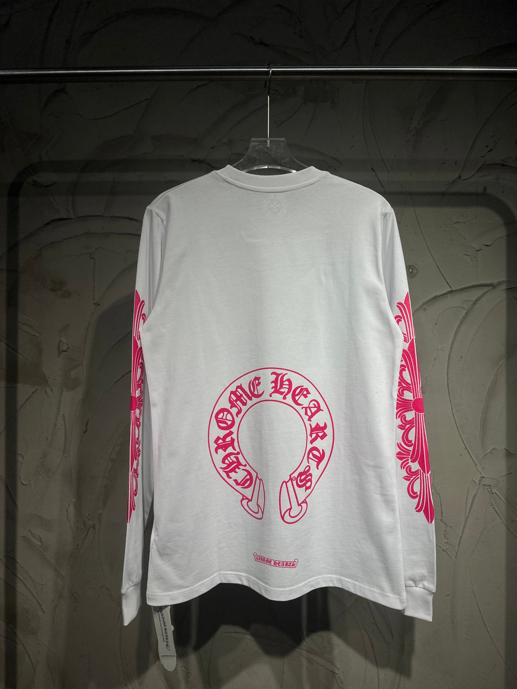 White long-sleeve T-shirt with large red-pink back logo and side sleeve scroll print.