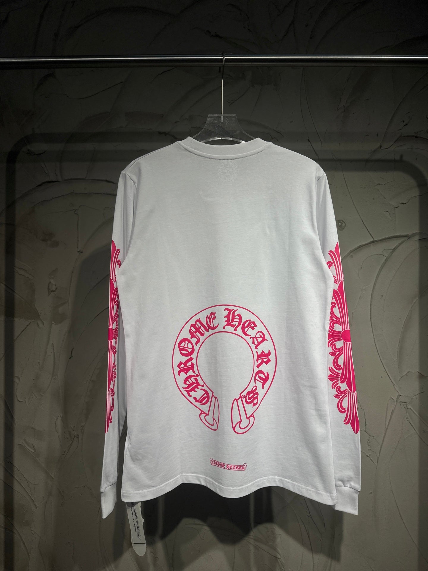 White long-sleeve T-shirt with large red-pink back logo and side sleeve scroll print.