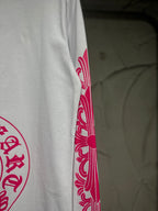 White long-sleeve T-shirt with red-pink sleeve scroll graphic near cuff.