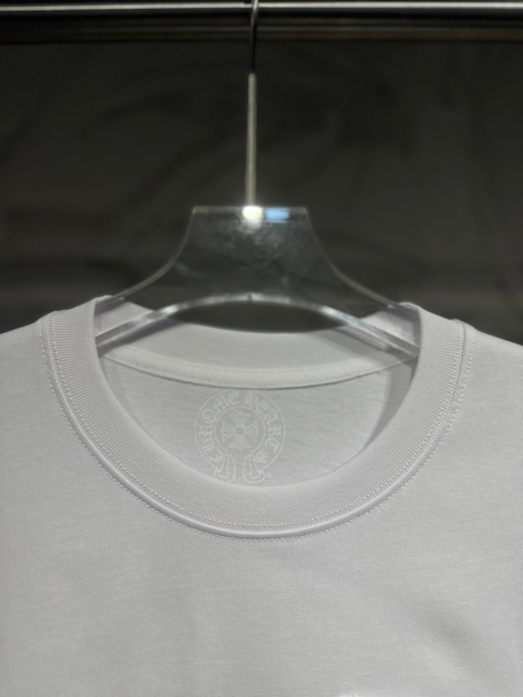 White long-sleeve T-shirt neckline and chest area with subtle circular logo print.