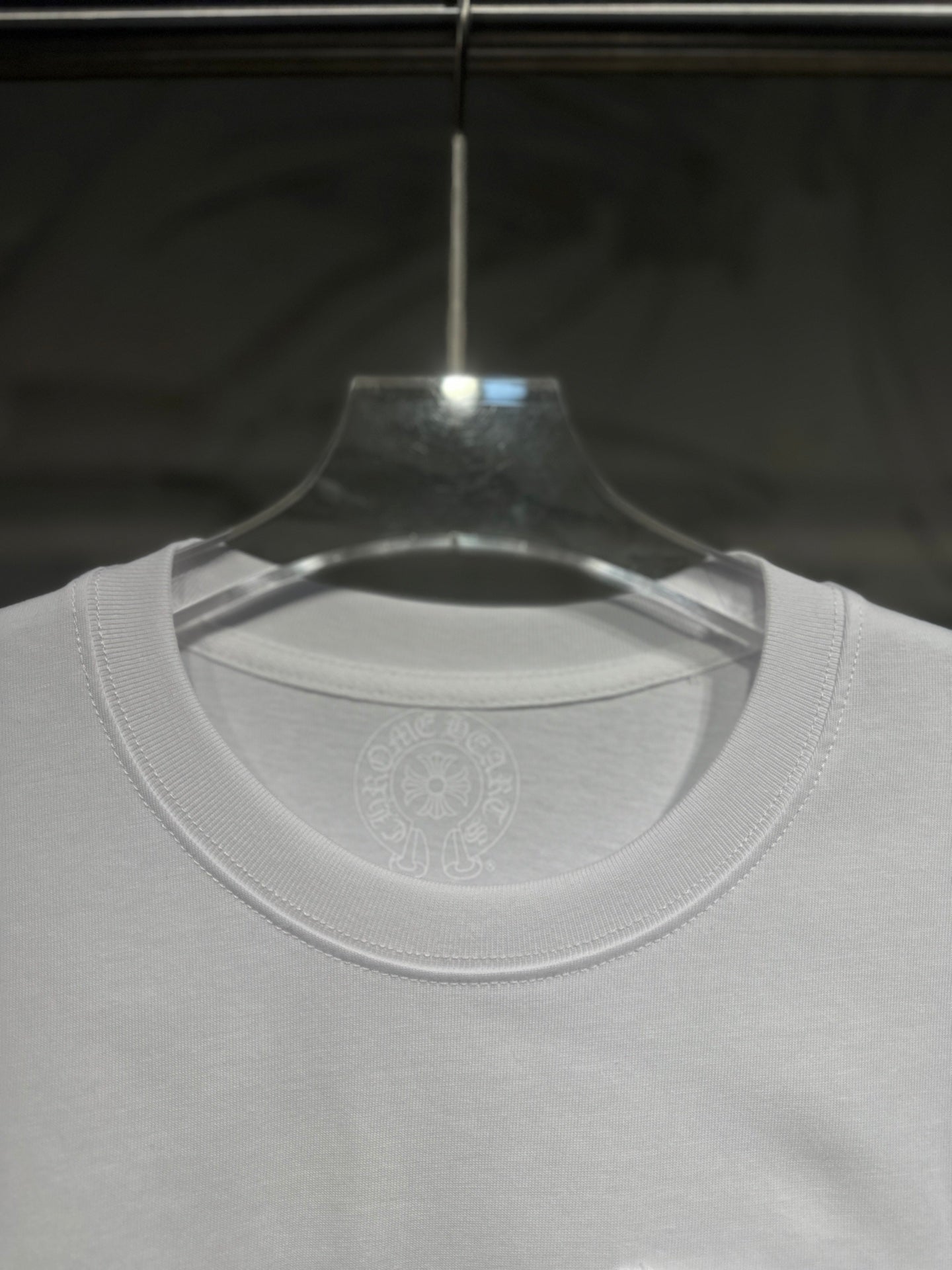 White long-sleeve T-shirt neckline and chest area with subtle circular logo print.