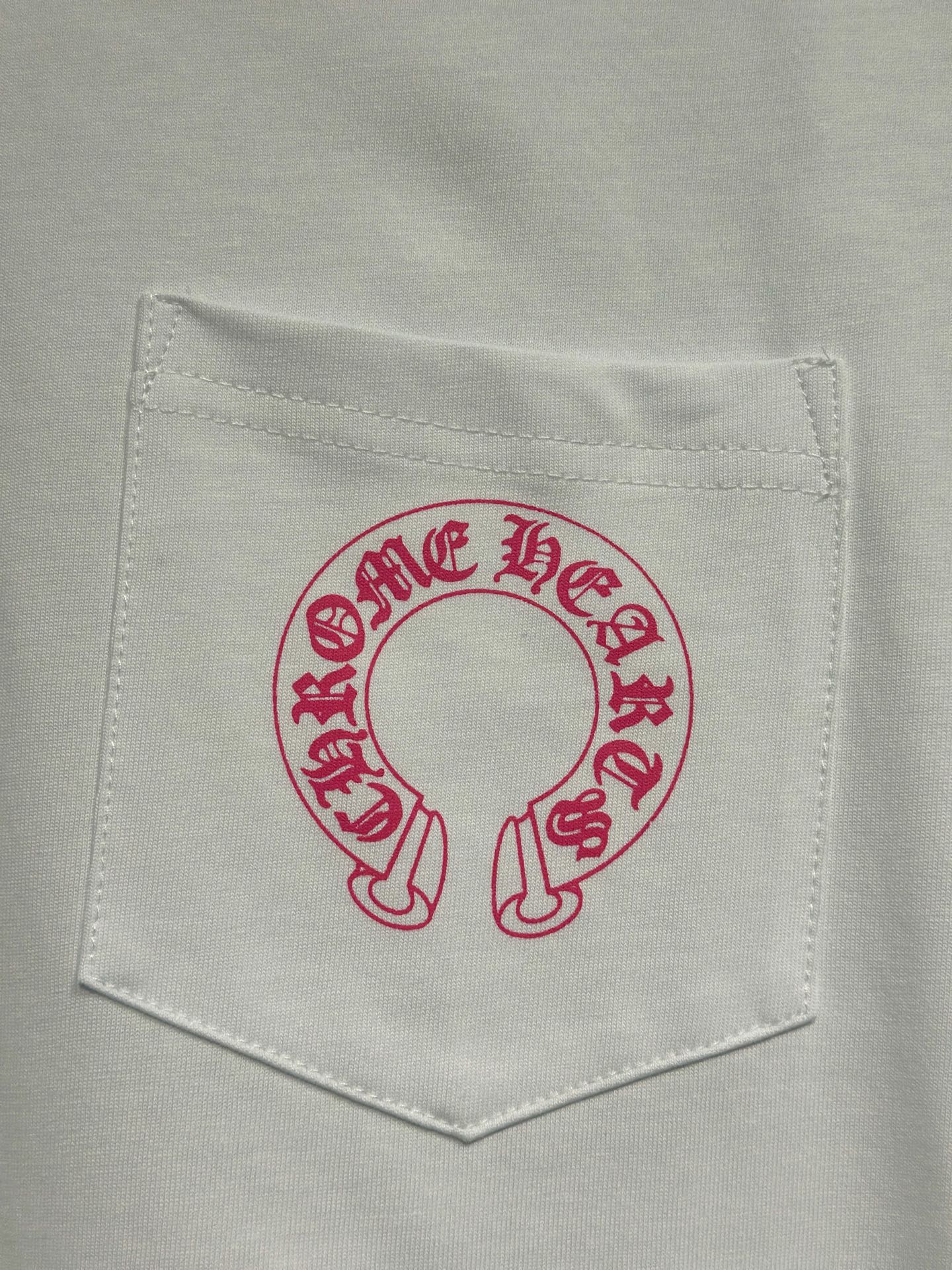 White long-sleeve T-shirt chest pocket with red-pink circular logo graphic.