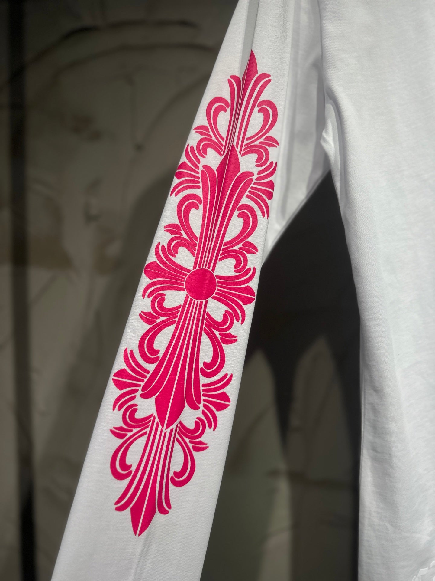 White long-sleeve T-shirt sleeve with large red-pink flower scroll graphic.