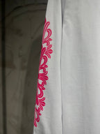 White long-sleeve T-shirt with red-pink floral scroll graphic on sleeve.