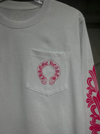 White long-sleeve T-shirt with red-pink logo patch on chest pocket.