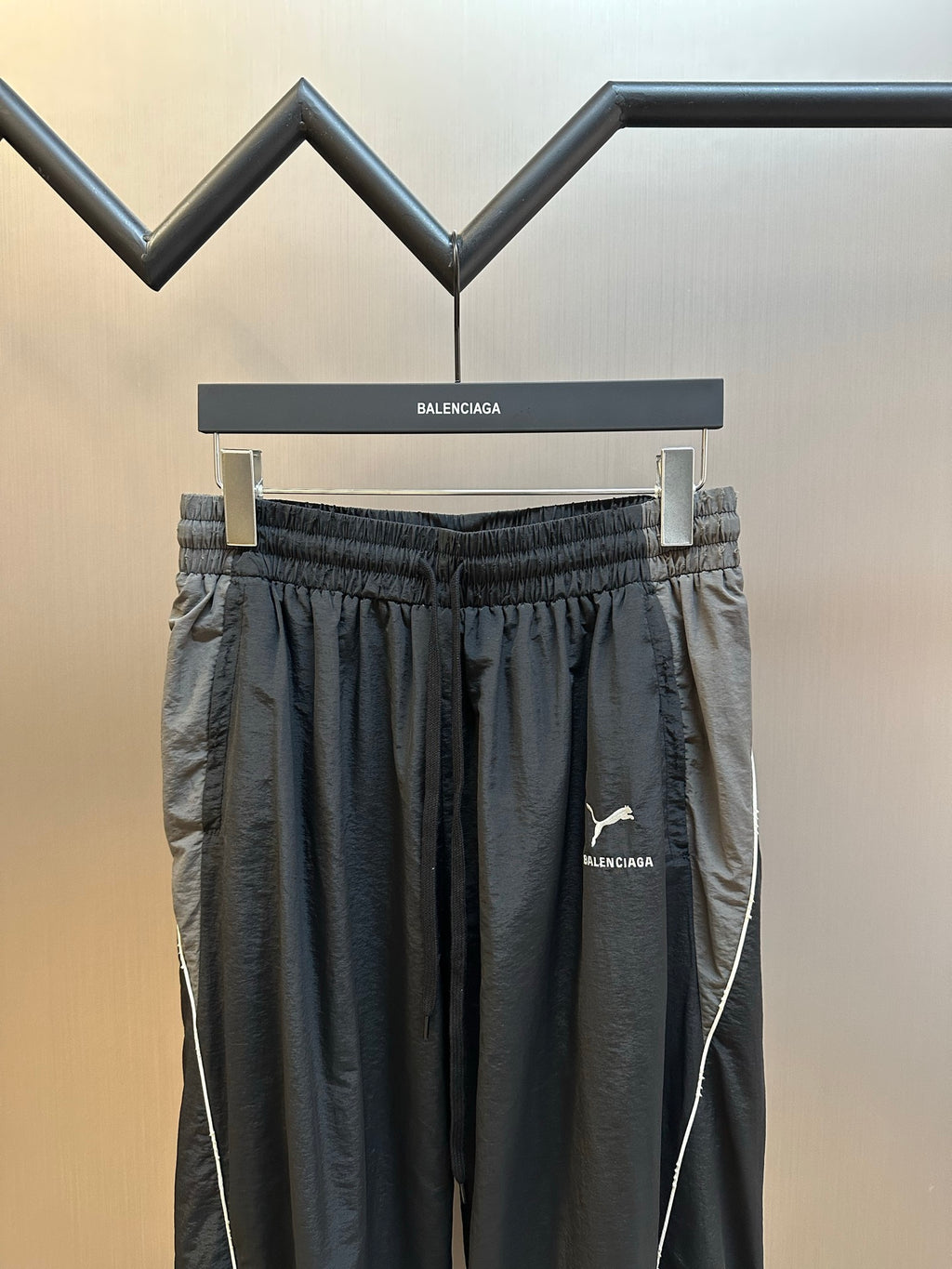 Dark navy track pants with elastic waistband, pleats, and contrast side seam piping
