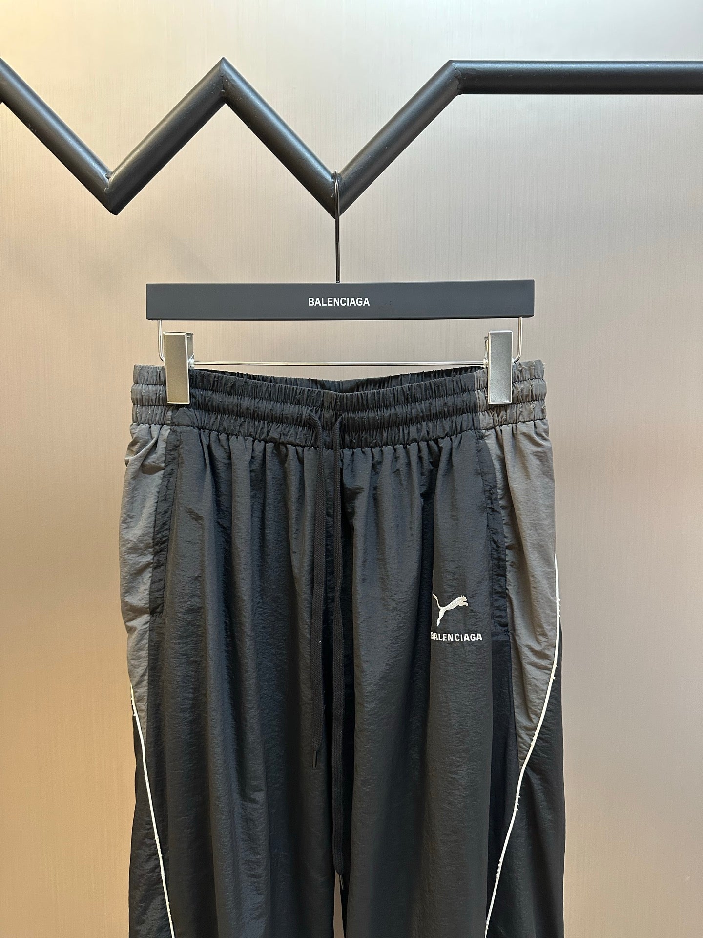 Dark navy track pants with elastic waistband, pleats, and contrast side seam piping