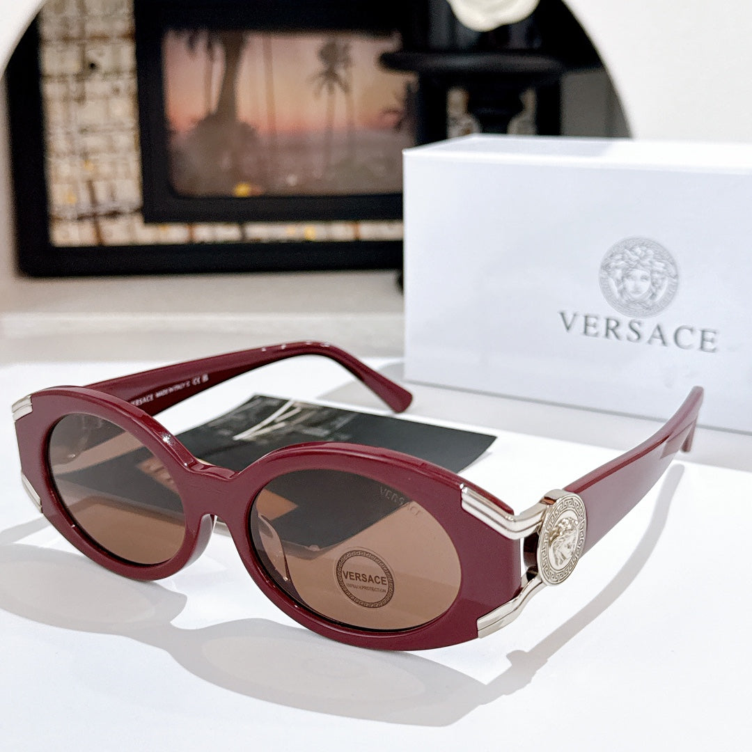 Versace sunglasses with dark lenses, burgundy frame, and gold logo detail on the temple