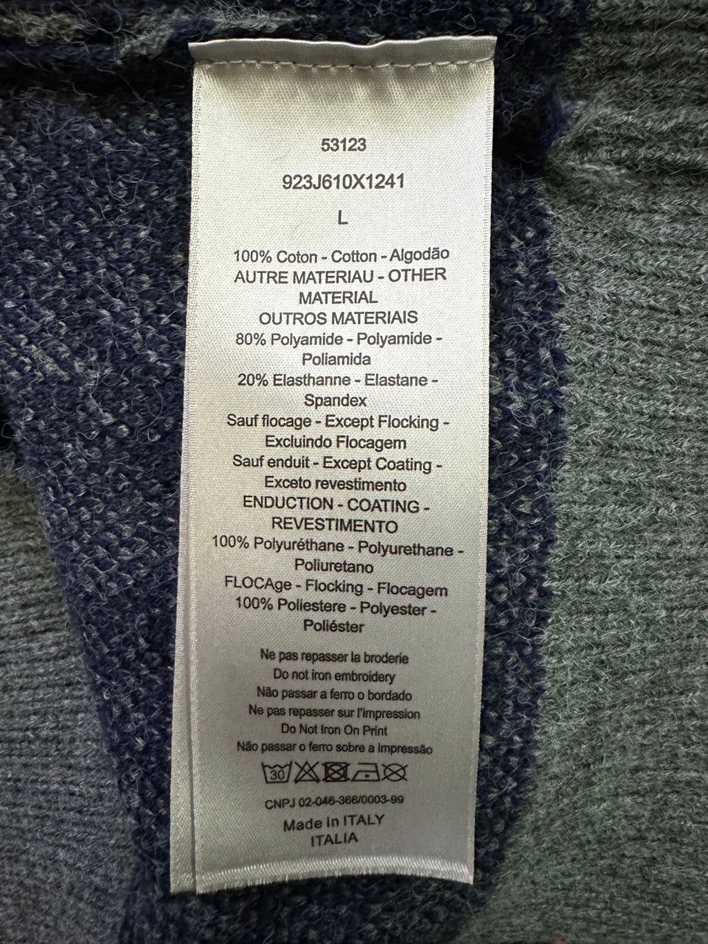 Dior clothing care label on dark knit fabric, size L and material blend details