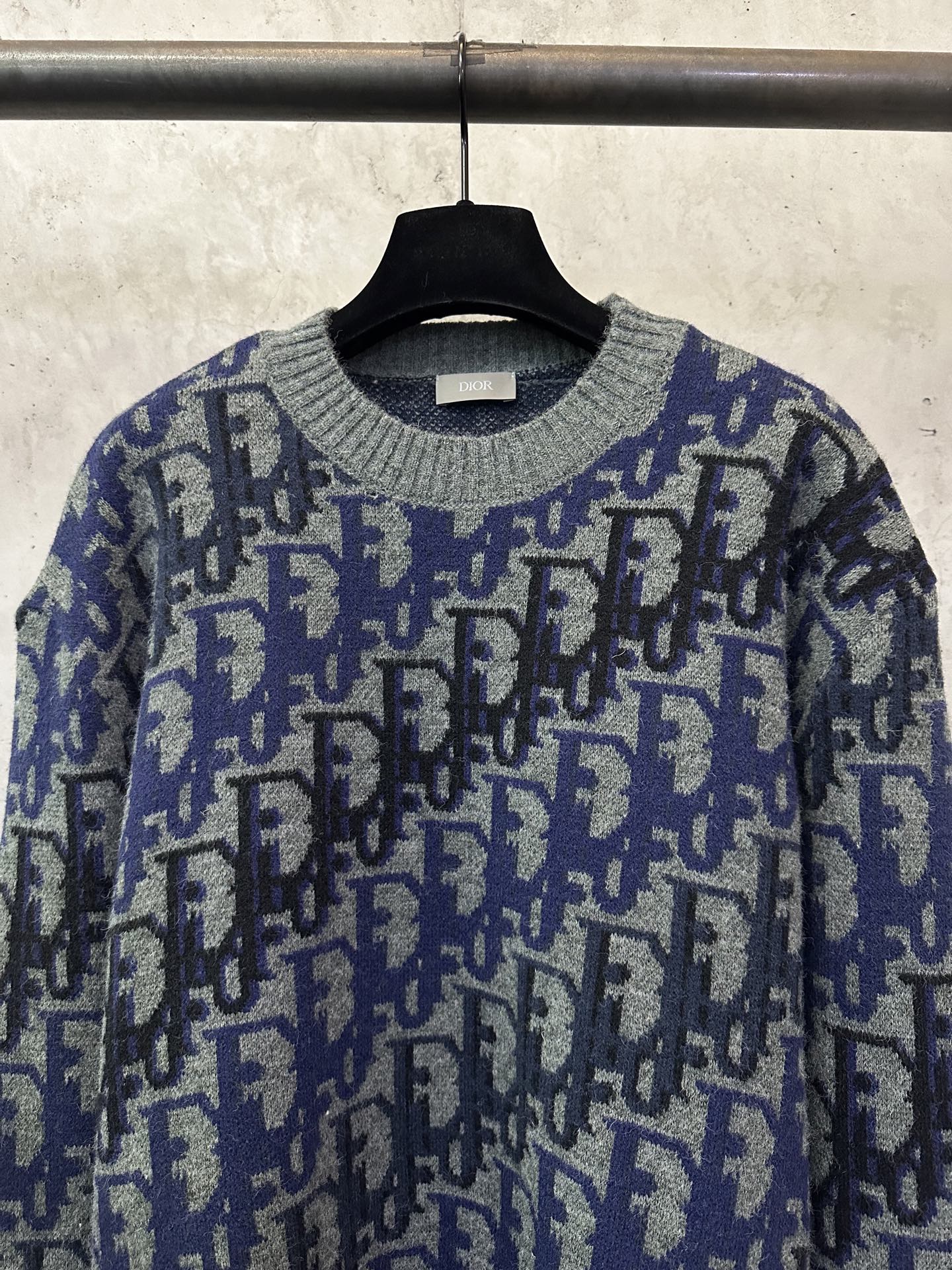 Dior knit sweater close-up with blue and black logo pattern and ribbed collar