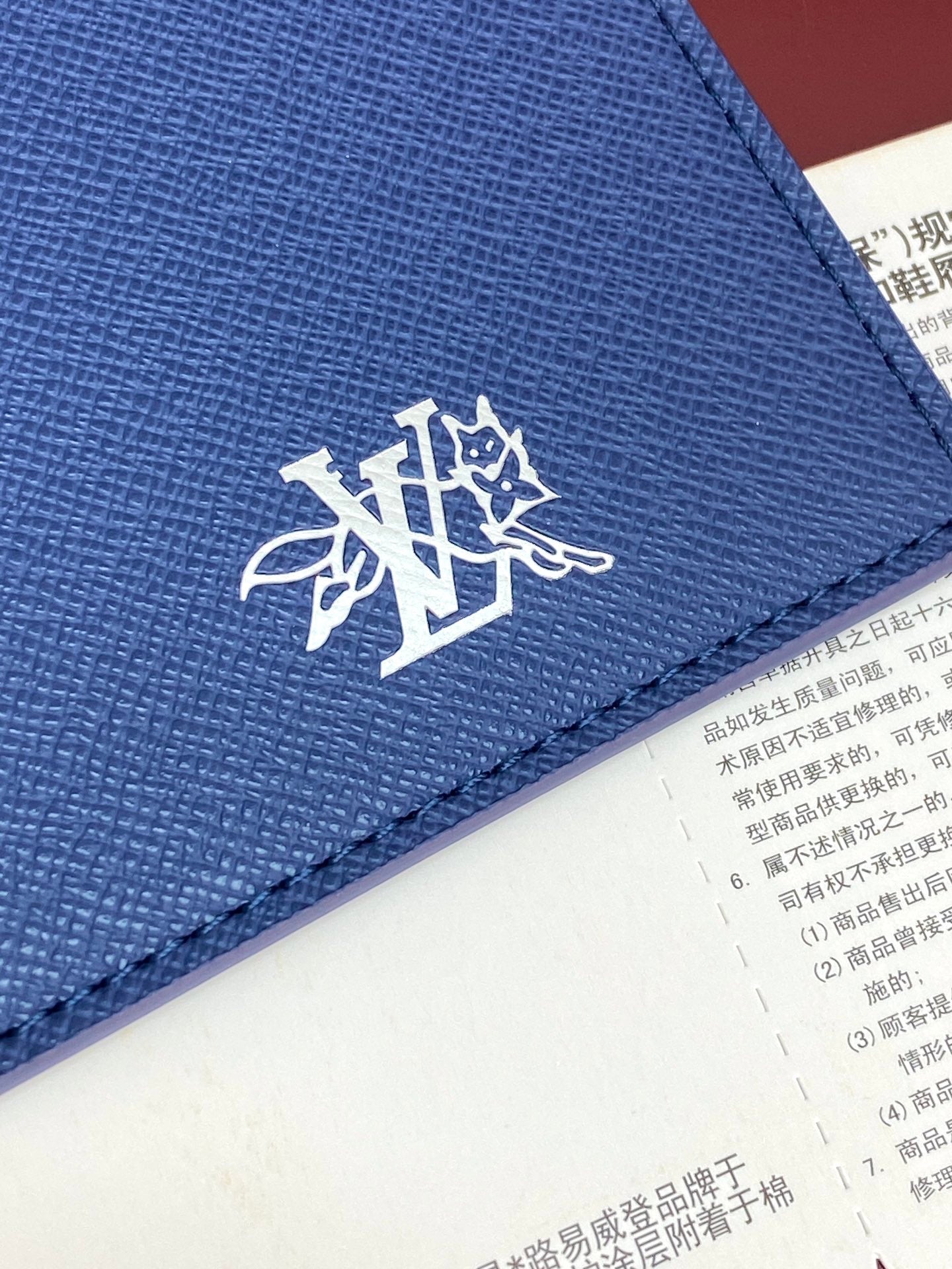 Blue Louis Vuitton small bag close-up of LV emblem with stitching along edge