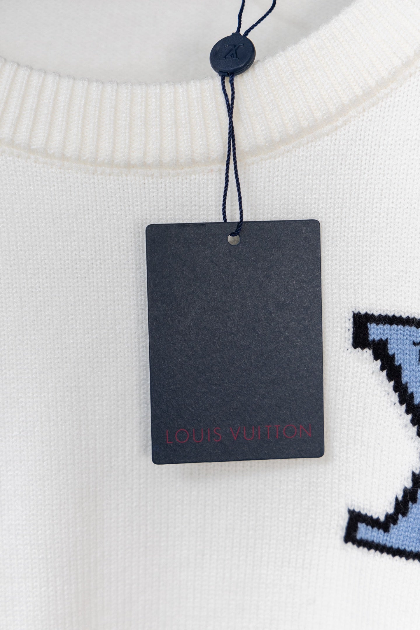 White sweater neckline with dangling hang tag and blue logo part