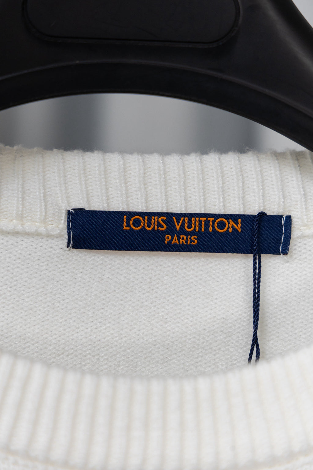 Neck tag on white knit sweater with “LOUIS VUITTON PARIS” label