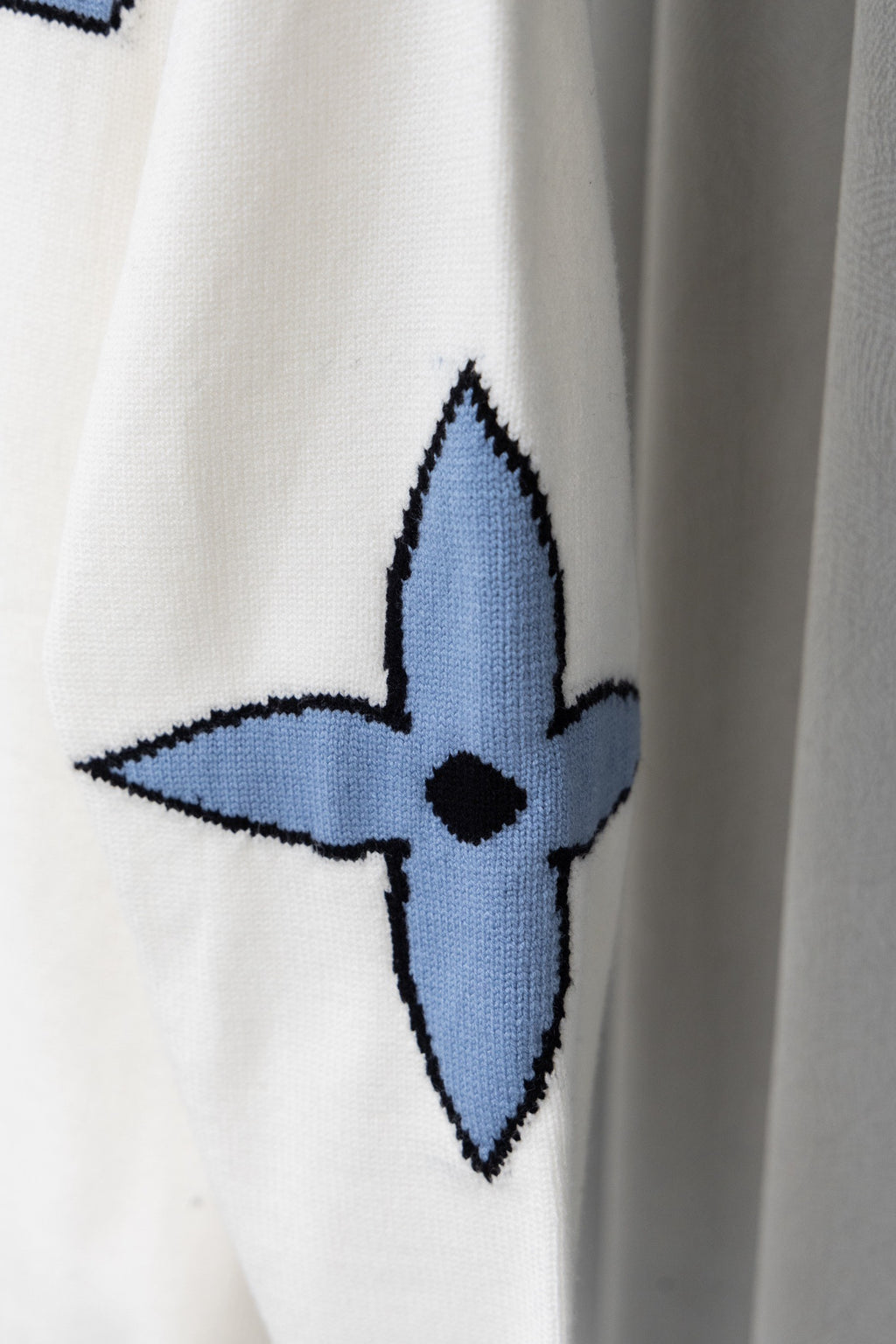 White sweater sleeve with blue emblem-style graphic