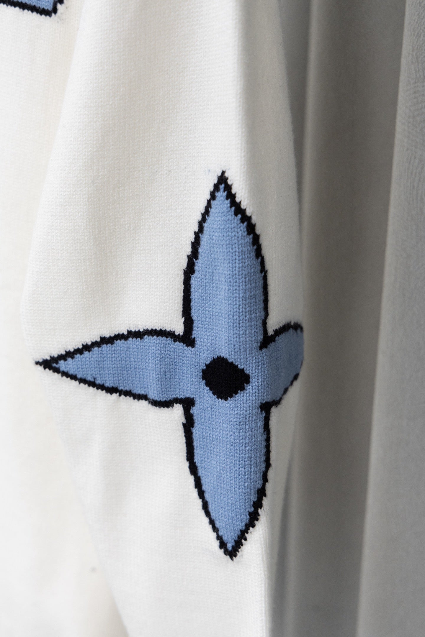 White sweater sleeve with blue emblem-style graphic