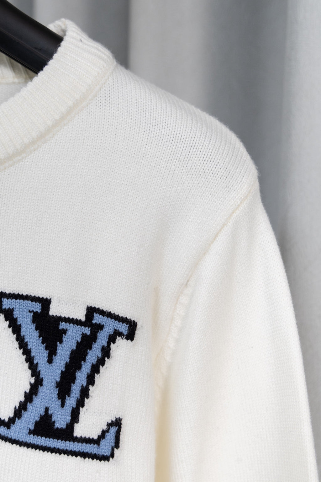 White sweater sleeve with partial blue logo graphic
