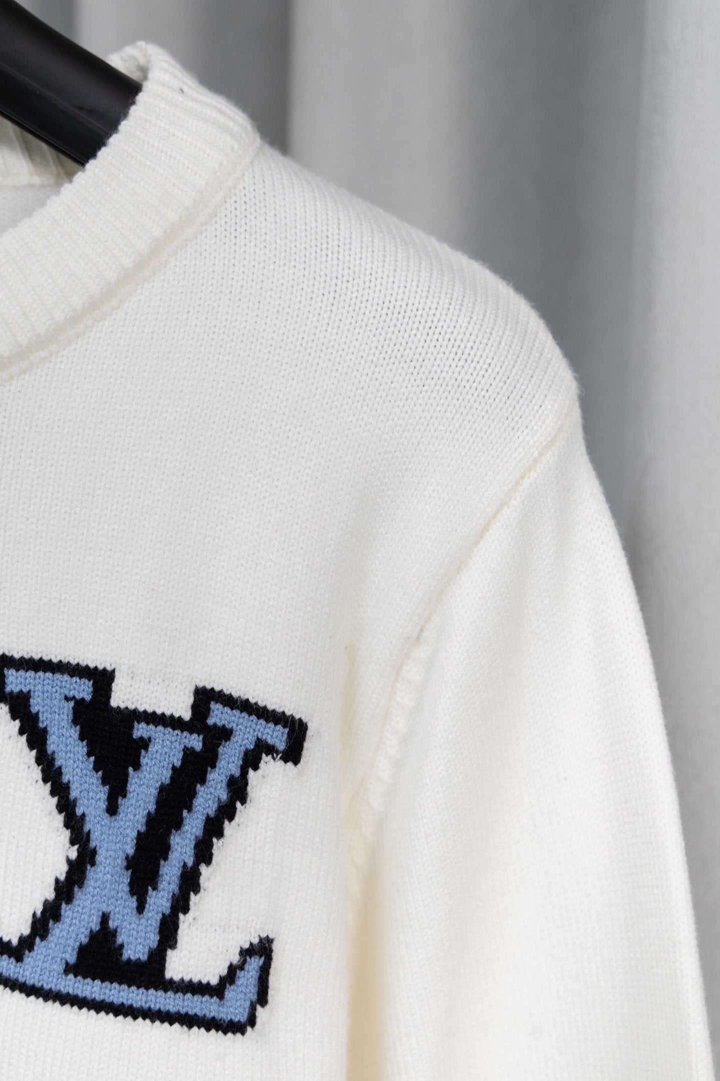 White sweater sleeve with partial blue logo graphic