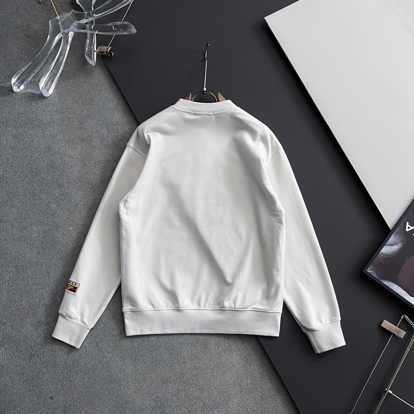 White sweatshirt back view with small sleeve cuff logo patch