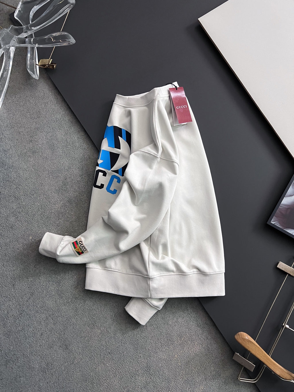 White sweatshirt draped with partial blue-and-black logo print and neck tag
