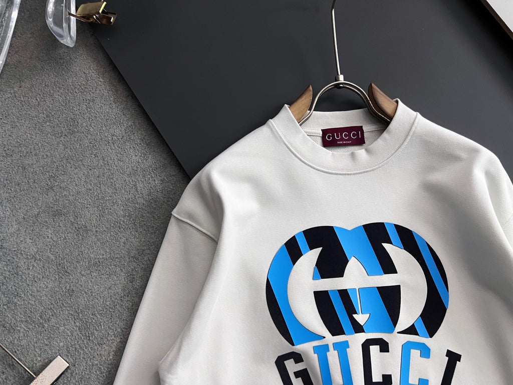White long-sleeve sweatshirt with large blue-and-black logo graphic and crew neck