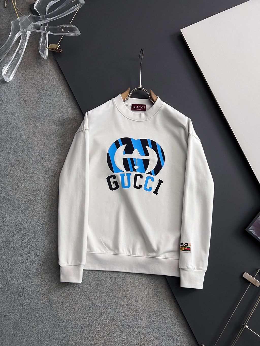 White long-sleeve sweatshirt with blue-and-black Gucci logo graphic on chest