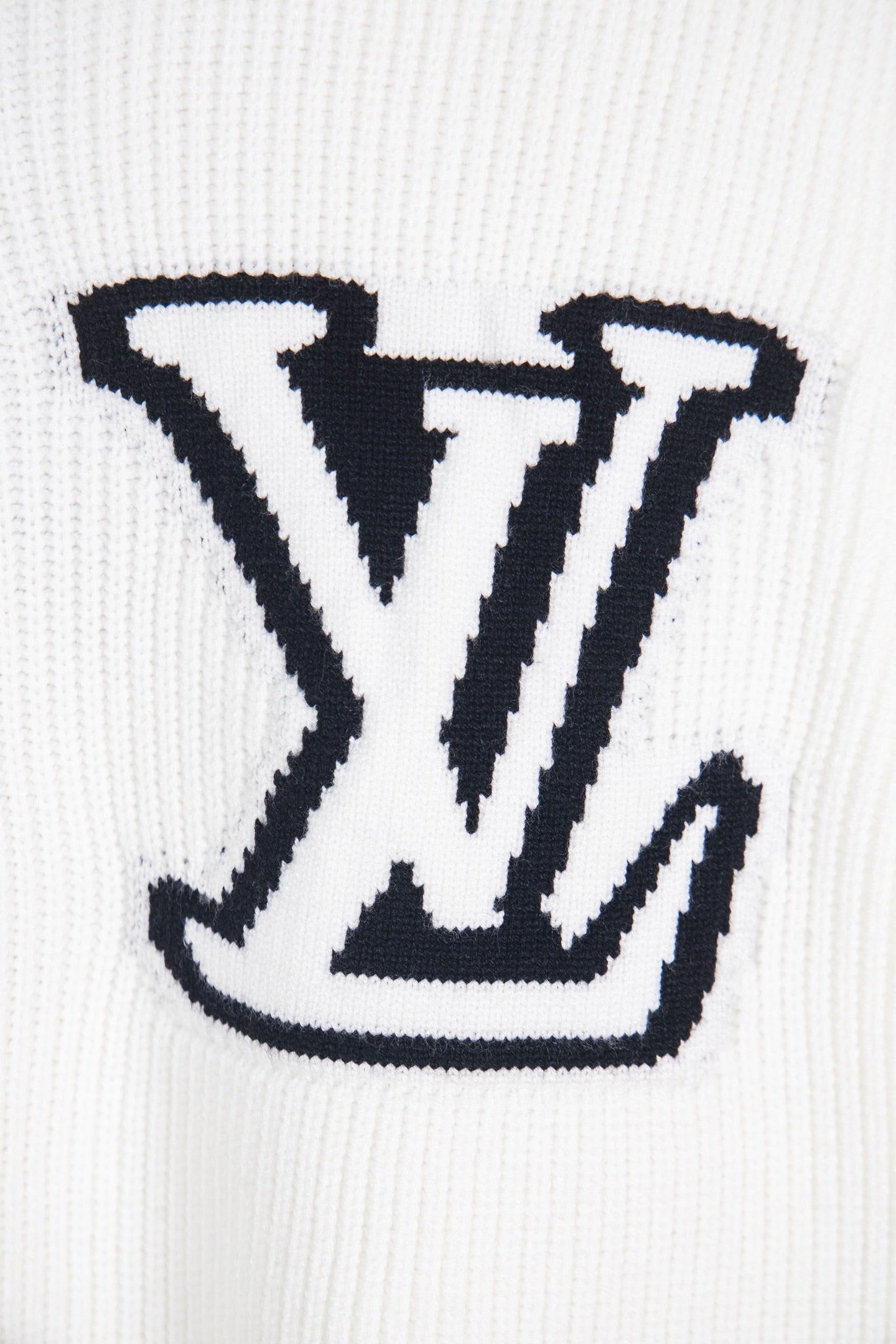 White knit sweater with oversized navy LV logo close-up