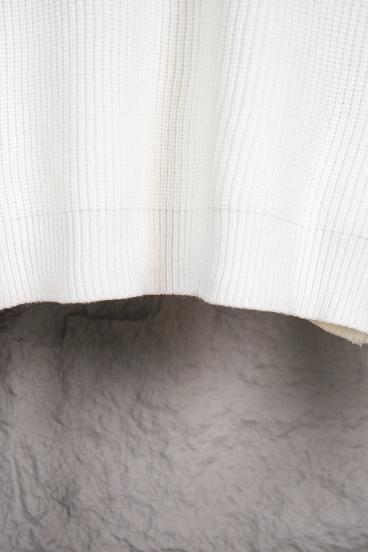 White ribbed knit sweater hem with curved bottom
