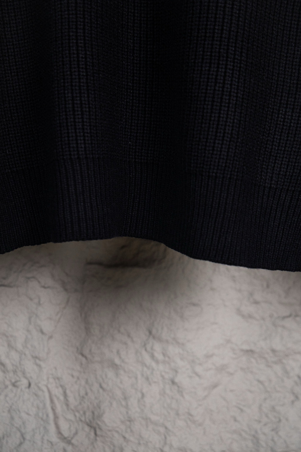 Dark navy knit sweater hem and back panel on hanger