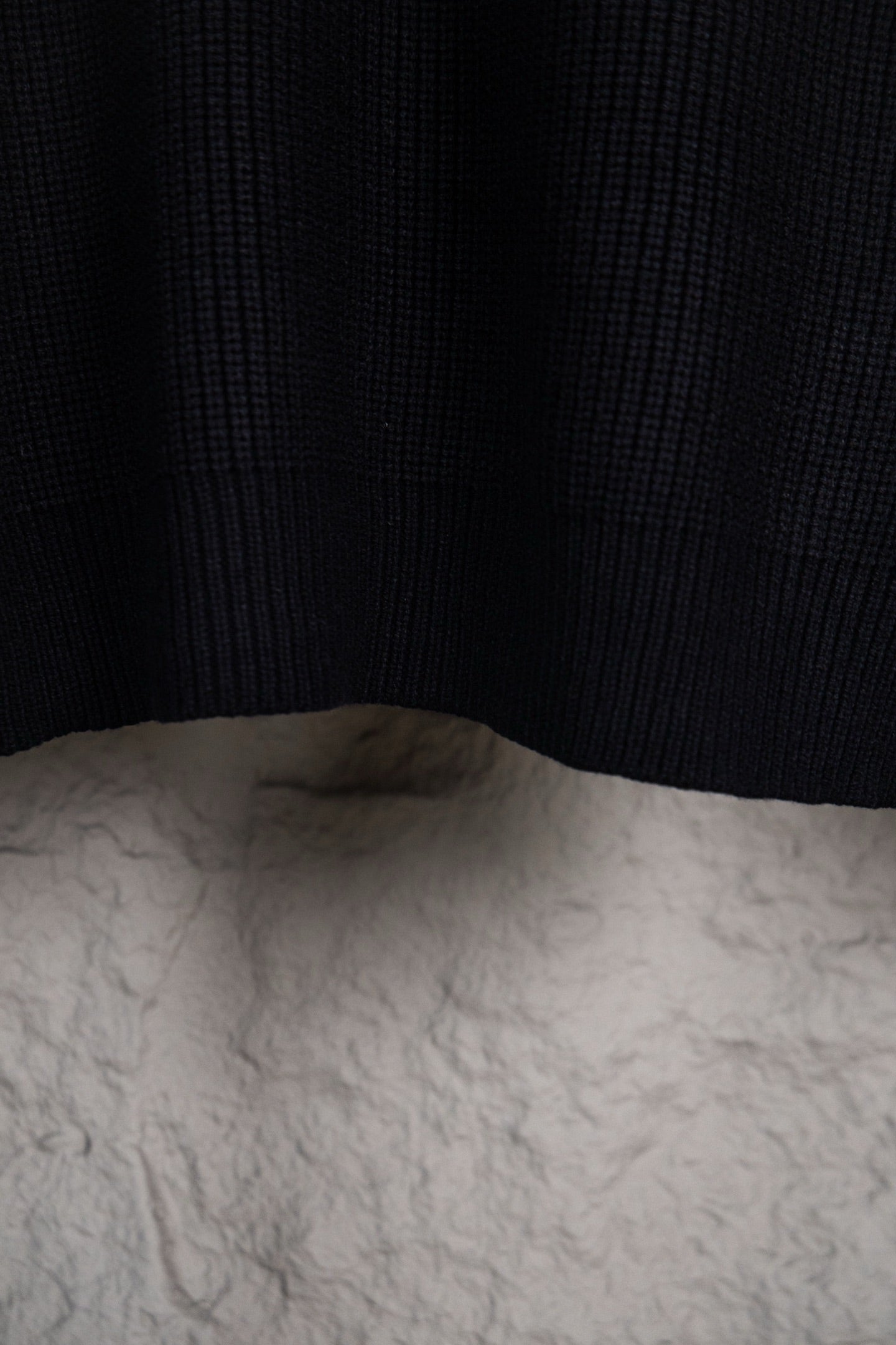 Dark navy knit sweater hem and back panel on hanger