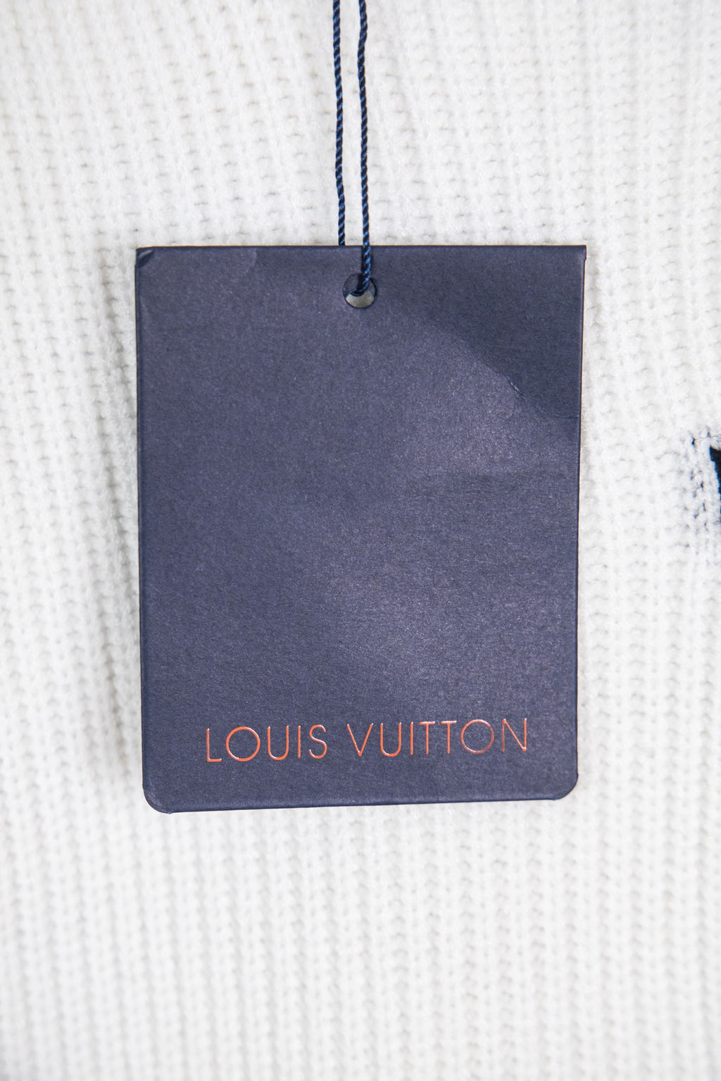 White knit sweater with navy Louis Vuitton hang tag