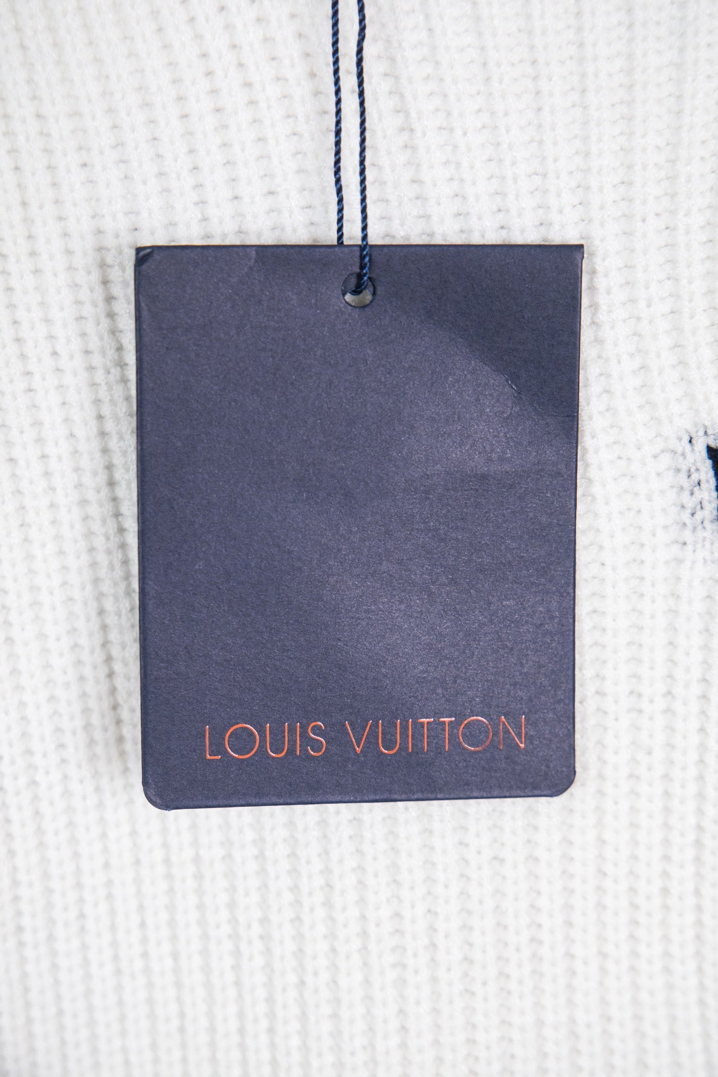 White knit sweater with navy Louis Vuitton hang tag