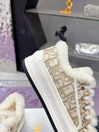 Side view of white low-top sneaker with beige monogram panel and fur-trimmed collar