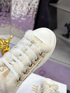 Close-up of white sneaker toe and lace panel with gold eyelets and fuzzy trim