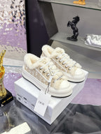 White low-top sneakers with faux fur lining and lace-up front; gold logo trim