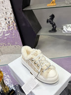 White low-top sneakers with beige monogram canvas and fluffy fur lining around the collar