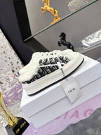 Low-top Dior sneakers with black logo-style textile, white laces, and faux-fur trim