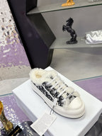 White Dior sneakers with black logo-style pattern, white laces, and fluffy collar