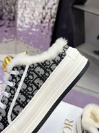 White Dior sneaker with black logo-style side, fluffy trim, and black-and-white laces