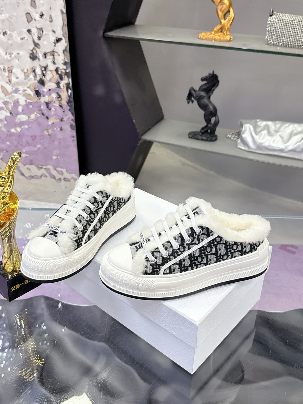Pair of white Dior sneakers with black patterned sides and fluffy shearling collar