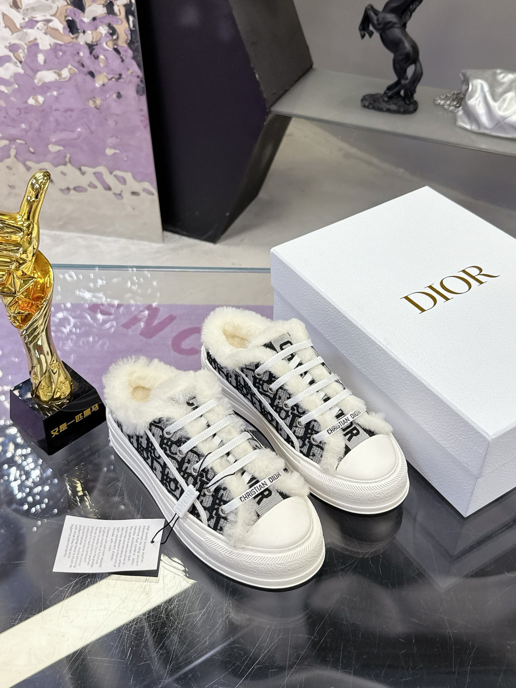 White Dior sneakers featuring black patterned stripe detail and fluffy white trim