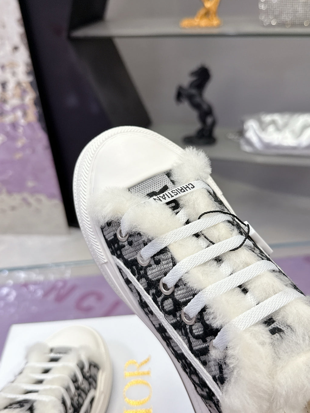 Dior sneaker with black patterned side panel, white laces, and fluffy inner trim